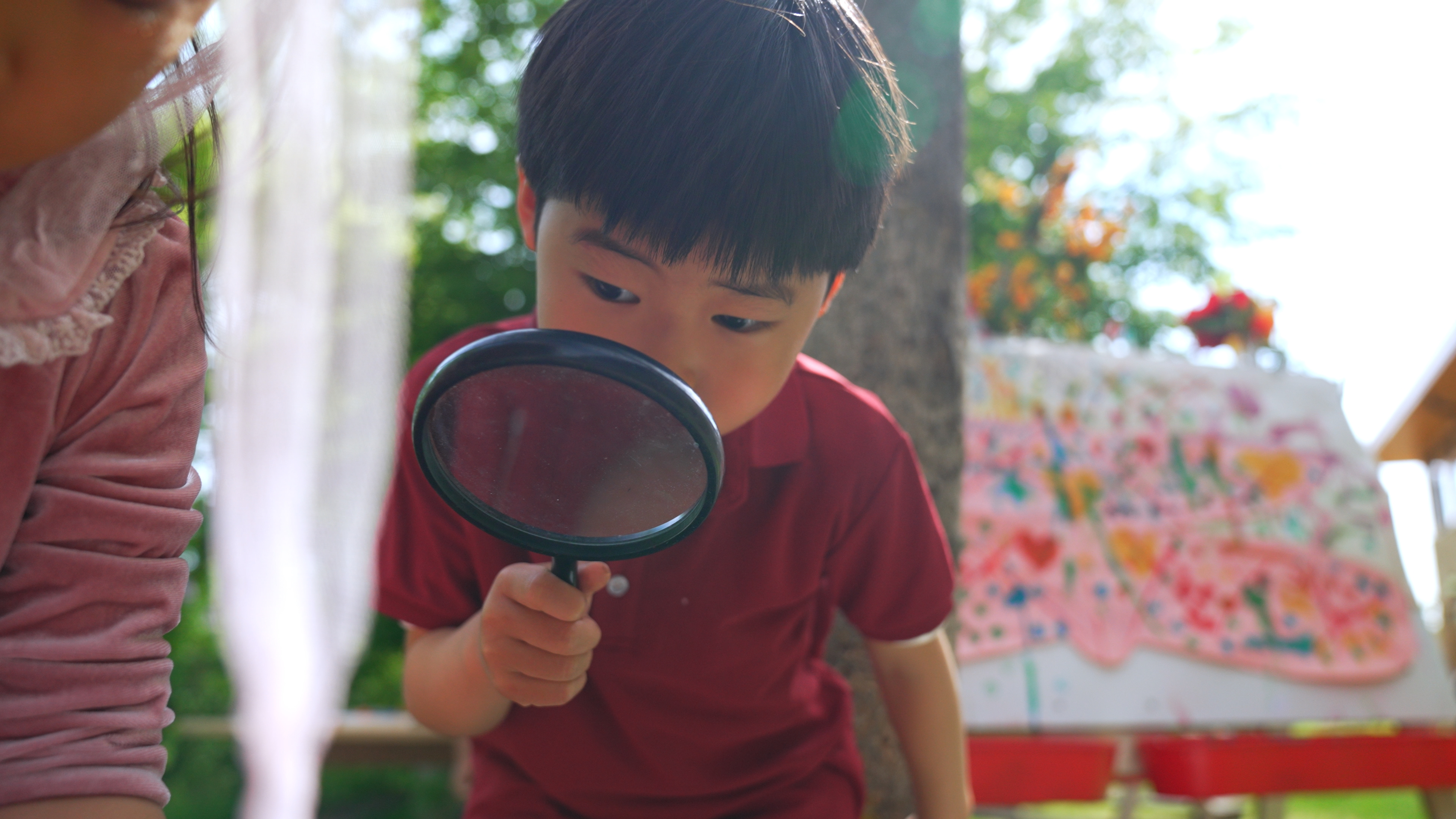 Child playing outside with a magnifier in spring observing nature