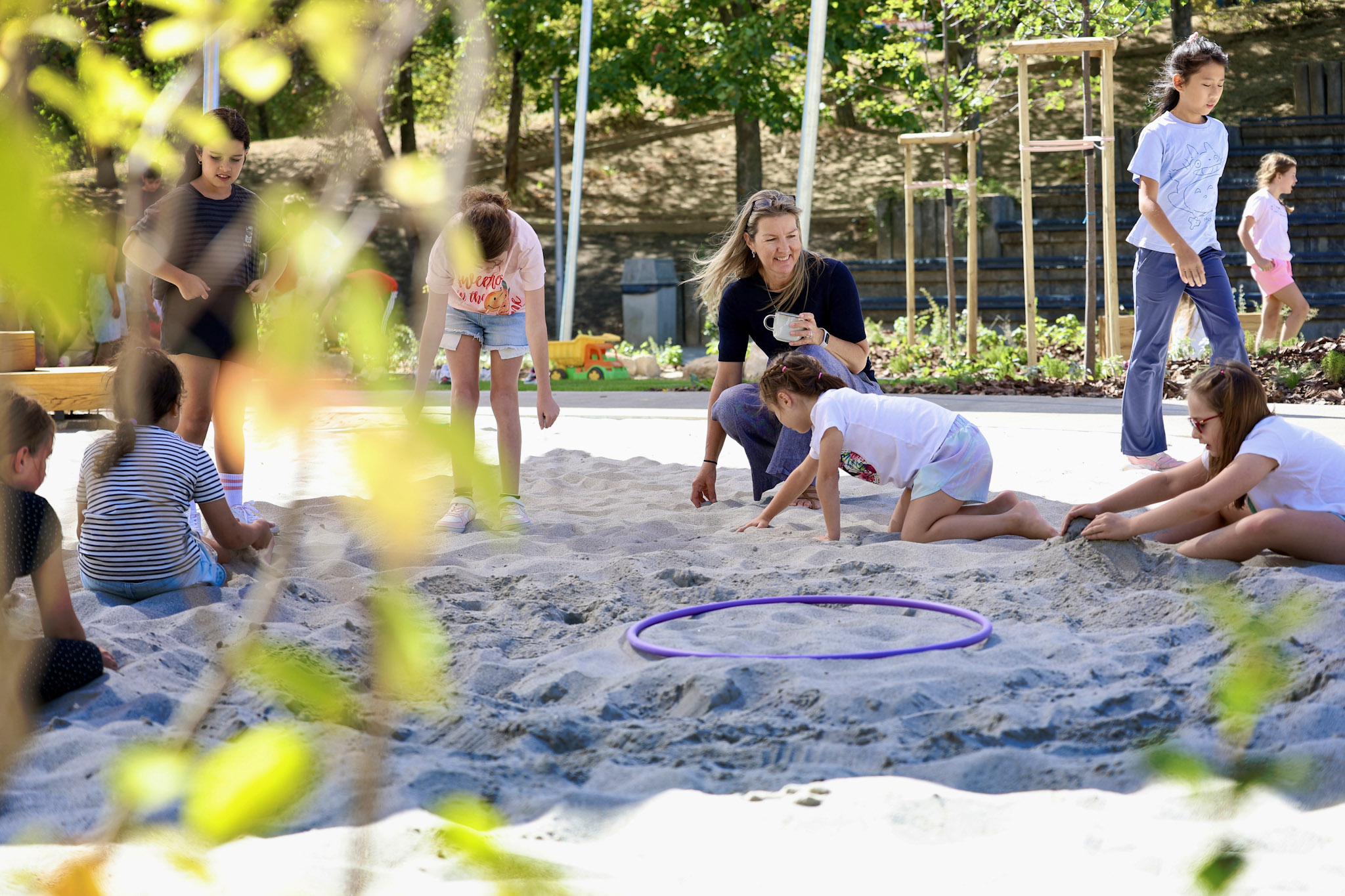 Students and teacher playing in the sand
